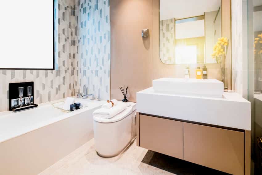 Bathroom with under sink cabinet, patterned wall tile, bathtub, and incinerating toilet