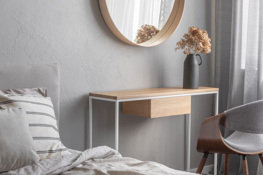 Bedroom with pillow, mirror, chair, vase, and bedside table