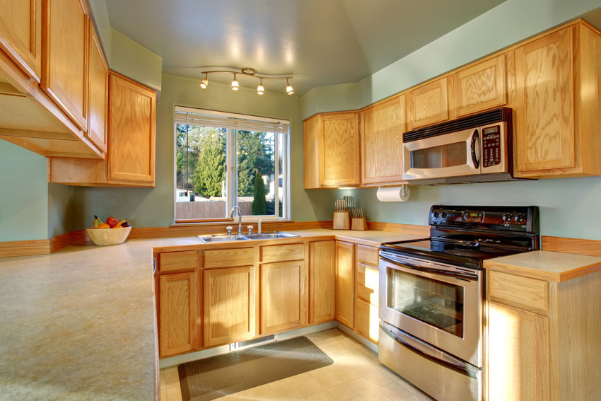 kitchen with sage, honey oak cabinets, oven, ceiling lights, and windows