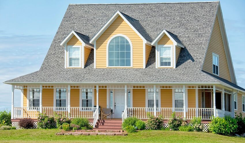 Large yellow country home with farmer's porch, asphalt shingle roofs